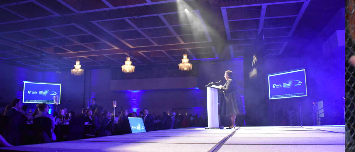 A woman speaks on a large stage with lighting and screens in the background